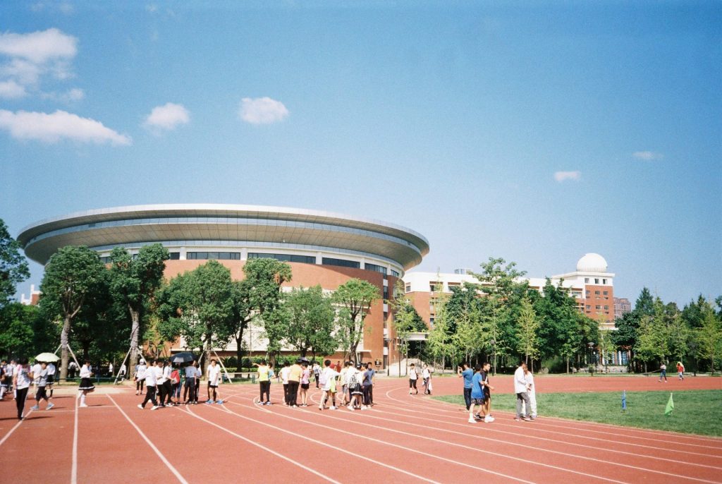 a group of people standing on a track in front of a building